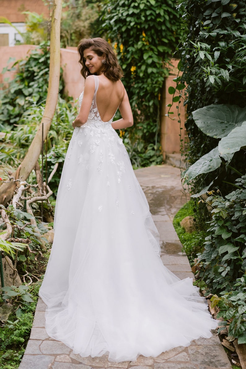 Imaginez vous dans cette robe de mariée envoûtante qui vous transportera dans un univers de féérie le jour de votre mariage. La dentelle florale en 3D ajoute une touche de magie, vous faisant étinceler sous les projecteurs.