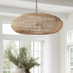 A stunning rattan pendant light is hung above a wooden farmhouse style kitchen island and 2 rustic flower vase