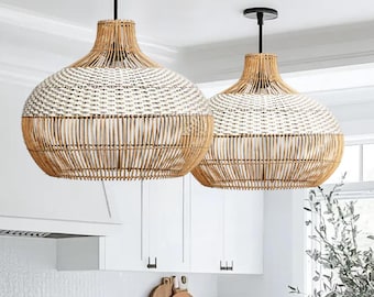 May include: Two white and brown woven pendant lights hang over a kitchen island with white cabinets and a white countertop. The island has a wood countertop and three bar stools.