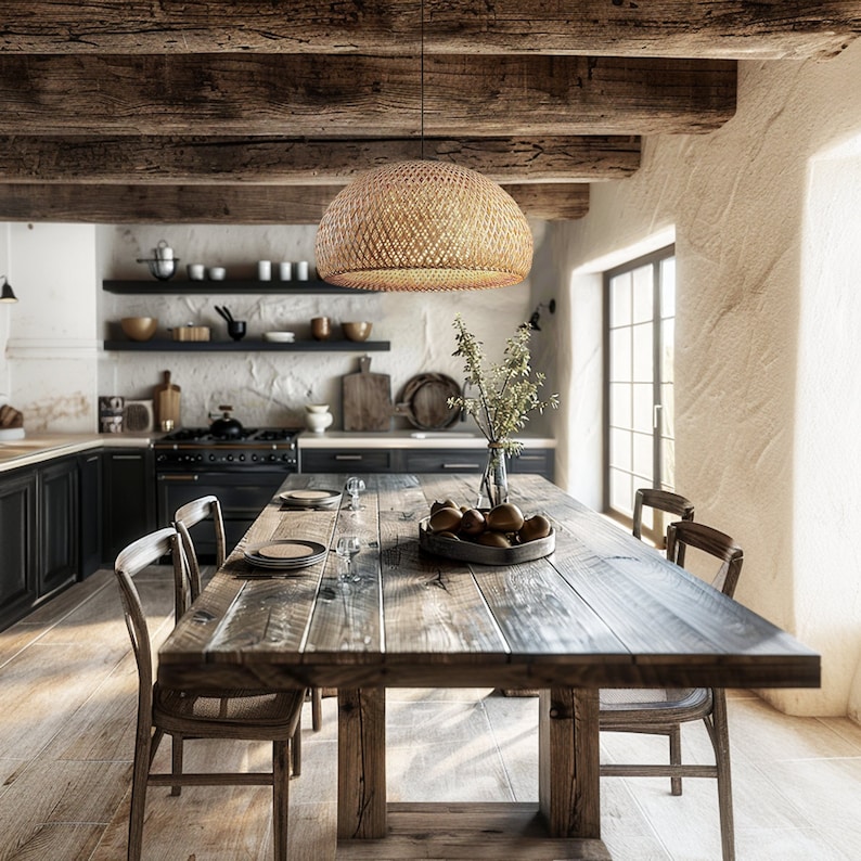 Op de afbeelding: Een rustieke houten eettafel met een geweven rieten hanglamp erboven. De tafel is gedekt met borden en glazen, en er is fruit in een kom op de tafel. De tafel is omringd door stoelen, en de kamer heeft een rustieke, boerderij-achtige sfeer.
