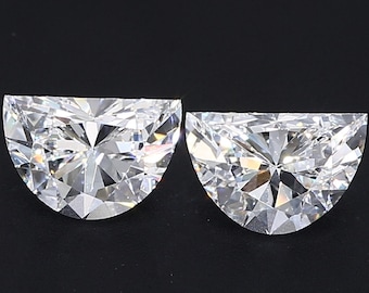 May include: Two brilliant-cut, half-moon shaped diamonds. The gems are clear and faceted, reflecting light. The diamonds are set against a black background, highlighting their sparkle and clarity. Ideal for jewelry making.