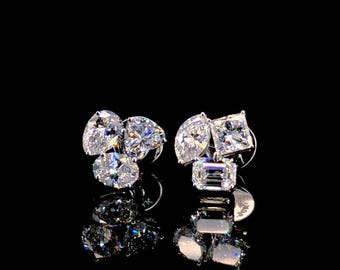 May include: A pair of silver stud earrings with four clear, faceted gemstones. The earrings feature a cluster of three round stones and one rectangular stone.