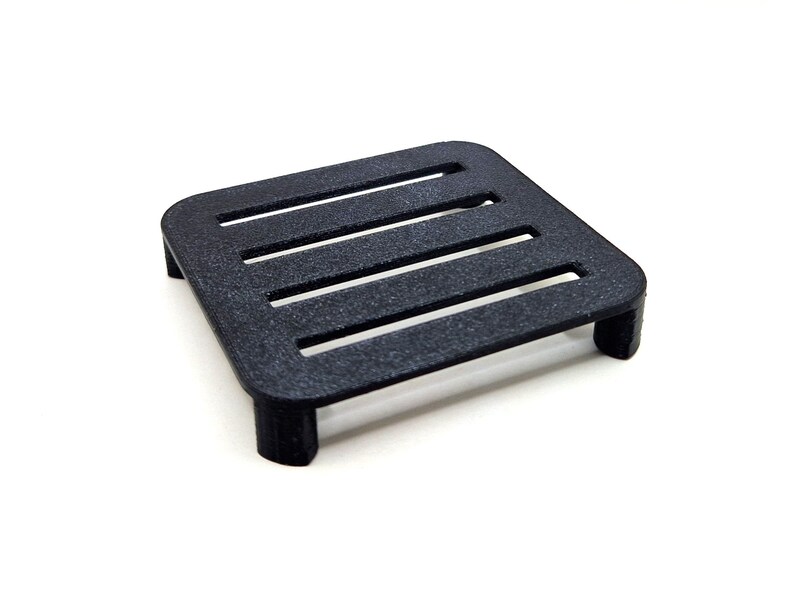 May include: A black plastic platform with five horizontal slats. The platform has four legs and is designed to elevate objects.