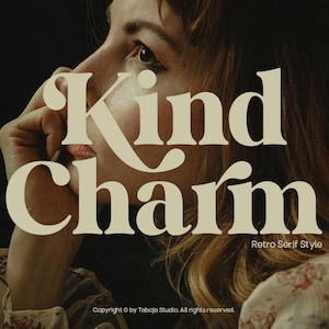 May include: A woman with long brown hair is looking off to the side. The text "Kind Charm" is superimposed over her face in a retro serif font style. The text "Taboja Studio" and "Retro Display" are in the top corners of the image.