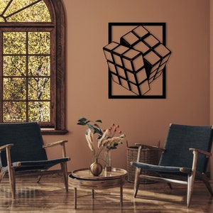 Pode incluir: Uma escultura de parede de metal preto de um cubo de Rubik 3D em uma sala marrom com duas cadeiras e uma mesa com um vaso de flores.