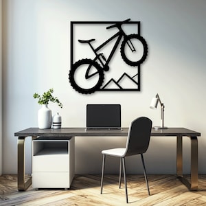 Pode incluir: Arte de parede de metal preto com a silhueta de uma bicicleta de montanha com uma cordilheira de montanhas no fundo. A bicicleta está enquadrada em uma forma quadrada.