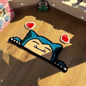 Unique handmade rug crafted with tufted technique, showing cute sleepy character in kawaii style, decorated with small floating hearts. Plush fluffy pile gives cozy comfortable feel. Perfect as anime rug, custom rug, or kawaii carpet for bedroom décor or nursery. Ideal handmade rug gift for couples, friends, or kawaii fans. Adds playful cheerful energy, cozy comfort, and colorful accent to room