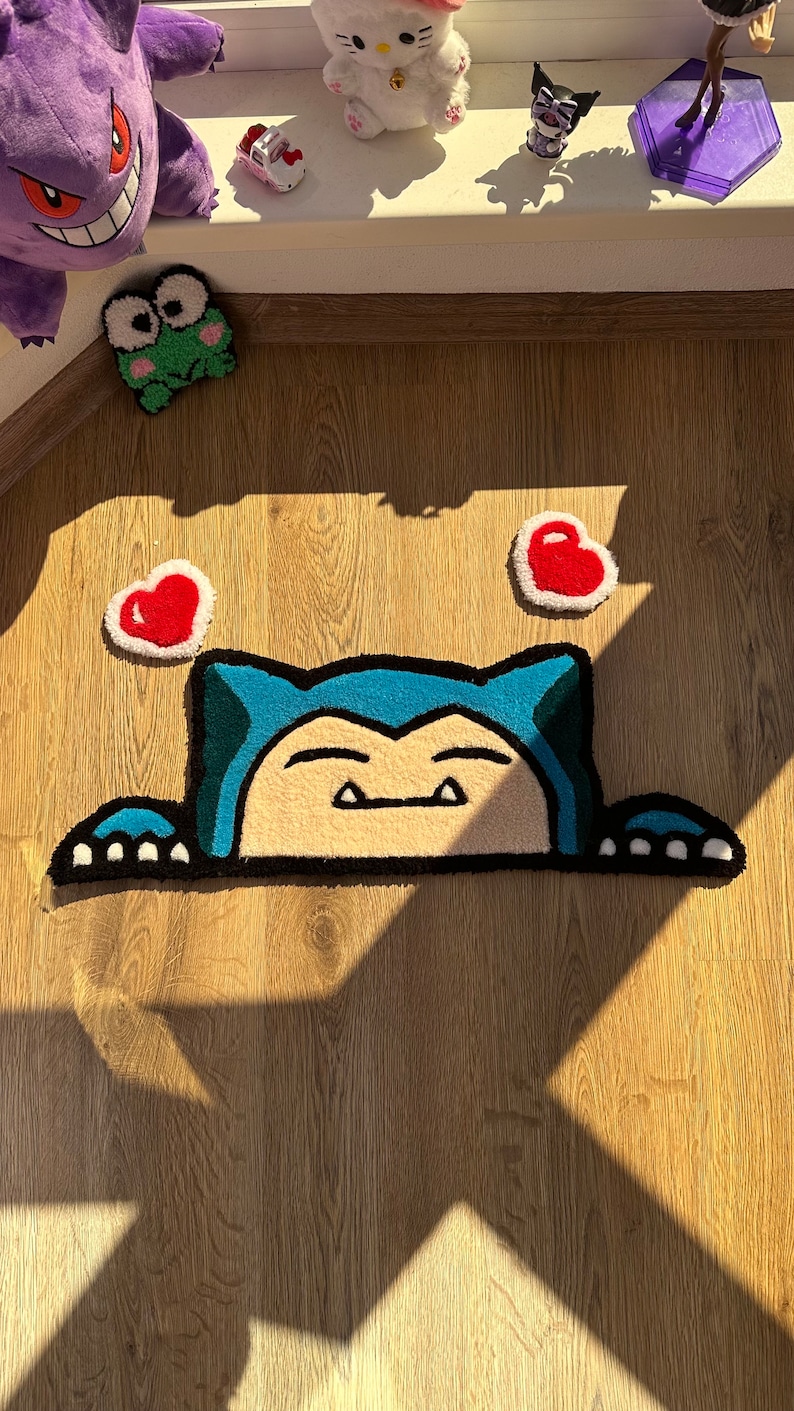Handmade tufted rug showing kawaii sleepy character peeking with blue ears and soft paws, surrounded by cute red hearts. Plush fluffy pile creates cozy soft texture. Perfect as anime rug, kawaii rug, or tufted carpet for bedroom décor, nursery, or studio. Unique handmade rug gift for fans of cute rugs, couples, or friends. Adds cozy charm, playful vibe, and romantic cheerful accent to interiors