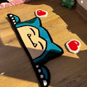 Unique handmade tufted rug in kawaii style, with sleepy blue character peeking and hearts around. Plush soft pile gives fluffy cozy comfort. Perfect as anime rug, cute carpet, or kawaii handmade décor. Great rug gift idea for couples, romantic vibe, or kawaii fans. Adds playful colorful accent, cozy charm, and cheerful energy to bedroom décor, nursery, or creative stylish spaces.