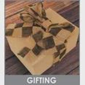 May include: A square gift box wrapped in tan paper and tied with a checkered ribbon. The ribbon features a pattern of black and tan squares. The box is on a wooden surface. The word "GIFTING" is in a gray box at the bottom.
