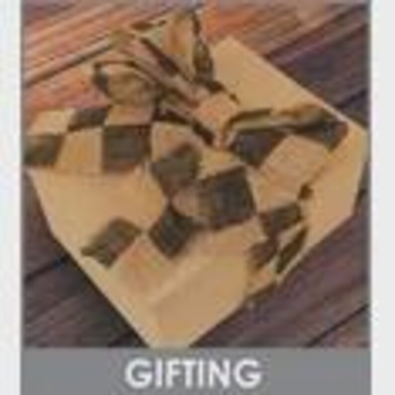 May include: A square gift box wrapped in tan paper and tied with a checkered ribbon. The ribbon features a pattern of black and tan squares. The box is on a wooden surface. The word "GIFTING" is in a gray box at the bottom.
