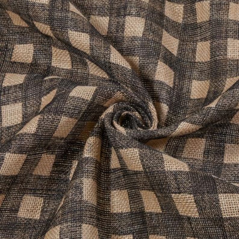 May include: Close-up of a fabric with a repeating checkered pattern. The fabric features a neutral color palette with a dark gray and tan checkered design. The fabric is folded and draped, showing the texture and weave.
