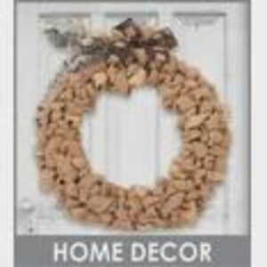 May include: A round wreath made of natural-colored materials, possibly wood or bark, with a decorative bow at the top. The wreath is hanging on a white door. The text "HOME DECOR" is at the bottom.