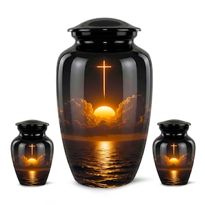 Könnte beinhalten: Ein Set aus drei schwarzen Urnen. Die Urnen zeigen eine Sonnenuntergangsszene mit einem Kreuz und einer hellen Sonne über dem Wasser. Die Urnen sind glänzend und haben eine klassische, abgerundete Form.