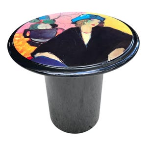 May include: A white ceramic mug with a black handle and the text "But First, Coffee" in a black, handwritten-style font. The mug is on a white surface.