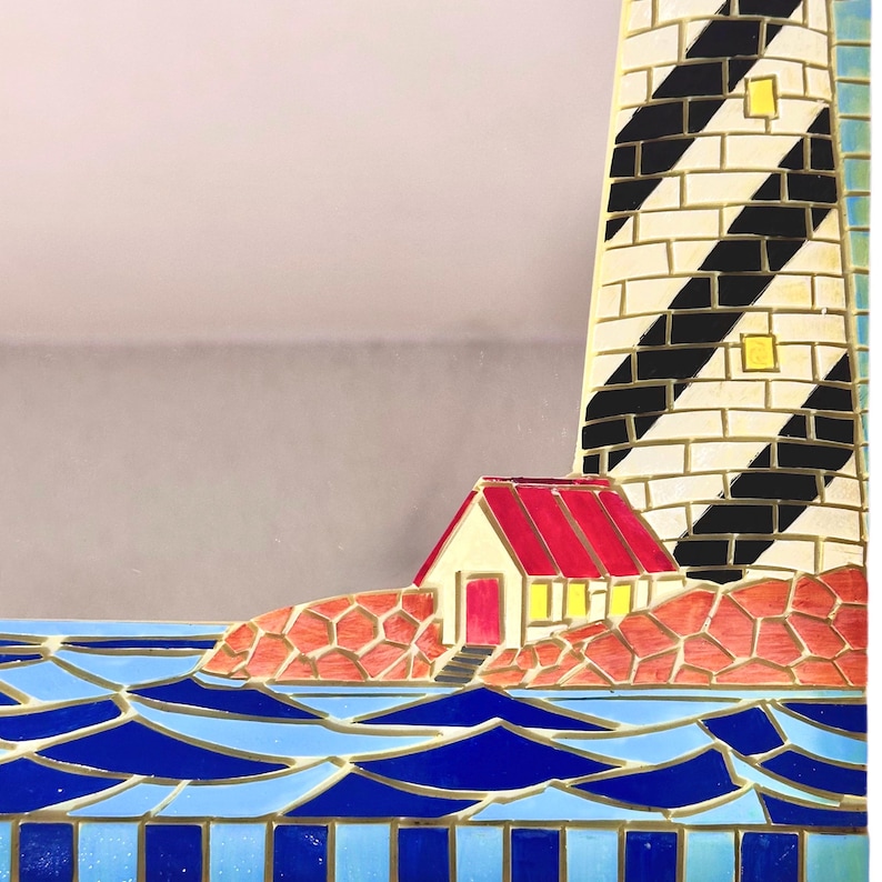 May include: A decorative lighthouse with a red-roofed building and blue water. The lighthouse has black and white stripes. The water is blue with white accents. The building is beige with a red roof.
