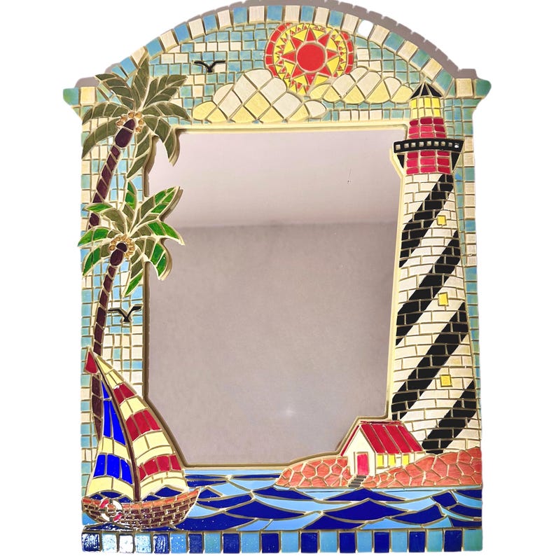 May include: A mosaic mirror with a coastal theme. The frame features a lighthouse, sailboat, palm tree, and sun. The mirror is rectangular with an arched top. The frame is made of colorful tiles in shades of blue, red, yellow, and green.