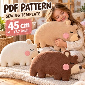 May include: A PDF pattern sewing template for a 45 cm or 17.7 inch bear-shaped plush toy. The design features three bears in white, tan, and brown, each with a light tan muzzle, a dark brown nose, closed eyes, and round pink felt cheeks.