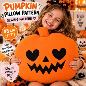 May include: A bright orange pumpkin-shaped cushion featuring a black jack-o'-lantern face with heart-shaped eyes and a jagged mouth. The cushion measures 45 cm. Text on the image includes PUMPKIN PILLOW PATTERN, SEWING PATTERN, and Digital Pattern PDF.