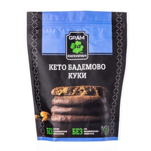 May include: A black resealable bag of keto almond cookies. The bag has a green clover logo with the text "GRAM за КИЛОГРАМ". The bag also has the text "КЕТО БАДЕМОВО КУКИ" and "БЕЗ ГЛУТЕН СТАБИЛИЗАТОРИ ЕМУЛГАТОРИ БЕЗ ΣΤΑ МОДИФИЦИРАНИ НИШЕСТЕТА".