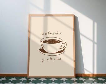 Op de afbeelding: Een ingelijste print met een illustratie van een koffiekopje en de woorden "cafecito y chisme". Het kunstwerk is uitgevoerd met bruine inkt op een crèmekleurige achtergrond. De lijst is van lichtkleurig hout.