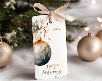 Könnte beinhalten: Ein weißer Geschenkanhänger mit einer Aquarell-Illustration eines blauen und goldenen Weihnachtsbaumes mit einem goldenen Band und grünen Blättern. Der Anhänger trägt den Text "An :" und "Von :" sowie die Worte "Frohe Weihnachten" in Kursivschrift.