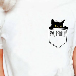 Peut inclure: T-shirt blanc avec un chat noir qui sort d'une poche sur laquelle est écrit "Ew, People!"