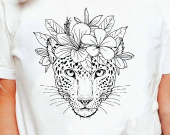 May include: A white t-shirt with a black line drawing of a leopard wearing a flower crown. The leopard's face is centered on the shirt and the flowers are arranged in a circle around its head.