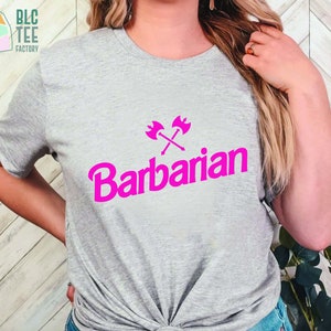 May include: A gray t-shirt with a pink graphic of crossed axes and the word "Barbarian" in a bold, pink font.