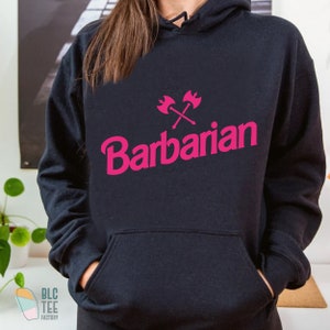 May include: Black hoodie with a pink graphic of crossed axes and the word "Barbarian" in a stylized font.