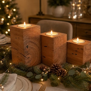 May include: Three rectangular wooden candle holders of varying heights, each featuring a natural wood grain finish and a circular metal insert at the top. Each holder contains a lit tea light candle, creating a warm glow on the wooden surfaces.