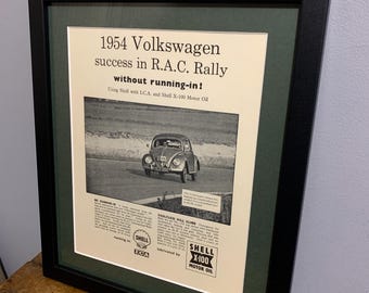 Peut inclure: Une publicité vintage en noir et blanc pour l'huile moteur Shell X-100 représentant une Volkswagen Beetle de 1954 roulant sur une route de terre. Le texte indique "1954 Volkswagen succès au rallye R.A.C. sans rodage ! Utilisant Shell avec LCA. et Shell X-100 Motor Oil."