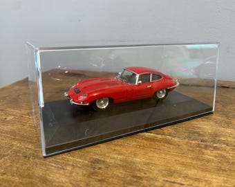 May include: A red vintage sports car model in a clear acrylic display case.