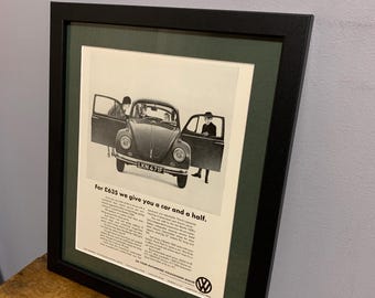 Peut inclure: Une publicité vintage en noir et blanc pour une Volkswagen Beetle. La publicité présente une photo d'une Volkswagen Beetle avec trois personnes debout autour d'elle. Le texte dit "Pour 635 £, nous vous offrons une voiture et demie."