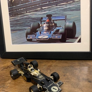 May include: A black and gold toy race car with the text "John Player Special" on the side. The car is a replica of a Formula One race car.