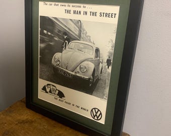 Peut inclure: Une publicité vintage en noir et blanc pour une Volkswagen Beetle. La publicité présente une photo de la voiture roulant dans une rue avec le texte "La voiture qui doit son succès à... L'HOMME DE LA RUE" et "LA MEILLEURE VALEUR AU MONDE".