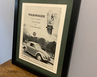 Peut inclure: Une publicité vintage en noir et blanc pour la Volkswagen Beetle. La publicité présente une photo de la voiture et le texte "VOLKSWAGEN par n'importe quel standard - la perfection dans l'artisanat".