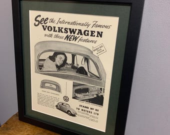 Peut inclure: Une publicité vintage pour la Volkswagen Beetle, mettant en scène une femme assise au volant. La publicité met en avant de nouvelles fonctionnalités, notamment un plus grand compartiment à gants, une lunette arrière plus large et une lunette arrière double. Le texte dit "Découvrez la Volkswagen, célèbre dans le monde entier, avec ces NOUVELLES fonctionnalités".