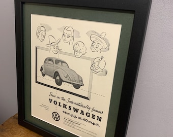 Peut inclure: Annonce publicitaire vintage en noir et blanc pour la Volkswagen Beetle. La publicité présente une illustration de la voiture en dessin animé avec un groupe de personnes qui la regardent. Le texte dit "Focus on the Internationally famous VOLKSWAGEN 46 m.p.g. at 40 m.p.h."