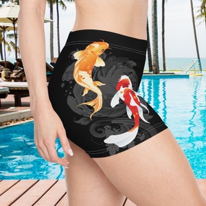Op de afbeelding: Zwarte sport shorts met een kleurrijk ontwerp van koi vissen. De vissen zwemmen in een draaiende beweging op een zwarte achtergrond.