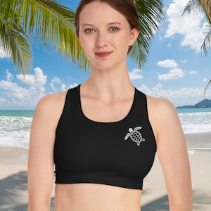 May include: Black sports bra with a white sea turtle graphic. The bra has a racerback style and is made of a stretchy, comfortable fabric.