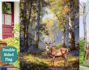 May include: A double-sided flag featuring a painting of a deer standing in a woodland setting. The deer is brown with large antlers and is surrounded by tall trees with green and yellow leaves. The flag is printed in the USA.