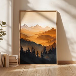 Peut inclure: Une impression d'art encadrée représentant une illustration de paysage de chaîne de montagnes au coucher du soleil. La scène montre des silhouettes sombres de pins au premier plan, passant à des collines et des sommets brumeux orange et jaune.