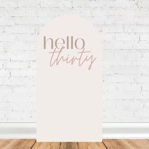 Op de afbeelding: Een witte boogvormige kartonnen uitsparing met de tekst "hello thirty" in roze letters.