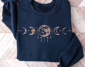 May include: A navy blue sweatshirt with a gold moon phase design. The design features a full moon, crescent moon, and half moon.