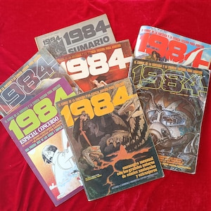 Peut inclure: Une collection de sept magazines de bandes dessinées de science-fiction et fantastique 1984 avec diverses illustrations de couverture, incluant une typographie audacieuse, des dessins détaillés et du texte en espagnol, disposés en éventail.