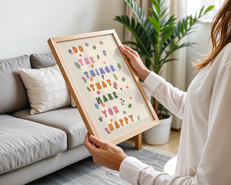 May include: A framed print with a light background and colorful text that reads "Do the things that make you happy". The text is surrounded by small floral illustrations in various colors.
