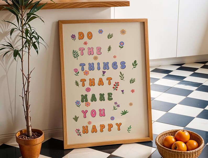 May include: A framed print with a light beige background and the text "DO THE THINGS THAT MAKE YOU HAPPY" in colorful, stylized letters. The letters are surrounded by small, colorful flowers and leaves.