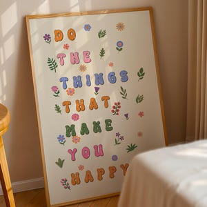 May include: A framed print with a white background and colorful letters that read "Do the things that make you happy". The letters are surrounded by small floral illustrations.