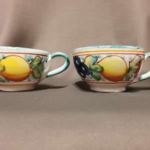 Pode incluir: Duas canecas de cer&acirc;mica branca com um design de lim&atilde;o e folha. As canecas t&ecirc;m um design verde, amarelo, laranja e azul.